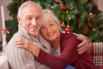 Image showing Christmas, love and portrait of a senior couple hugging, bonding and relaxing on a sofa together. Happy, smile and elderly man and woman in retirement celebrating xmas at a festive party at home.