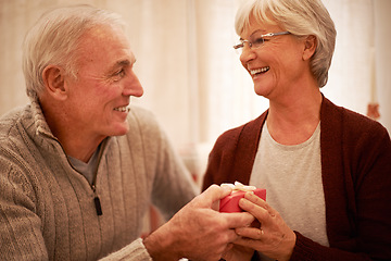 Image showing Senior couple, love and gift in house or home living room for valentines day, marriage anniversary or birthday celebration. Smile, happy or retirement elderly man and woman bonding with present box