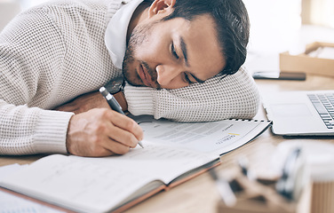Image showing Bored, writing and diary with a business man lying on his desk at work while making note of an appointment. Schedule, calendar and notebook with a male employee working on an idea while feeling tired