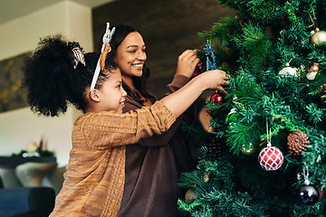 Image showing Mother, girl and bonding with christmas tree decoration in family home or house for celebration event, festive holiday or vacation. Smile, happy or xmas woman and child hanging lights, balls or decor