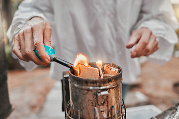 Image showing Hands, fire and beekeeping with a woman farmer using a smoker in the production of honey in the countryside. Agriculture, farm and sustainability with a female beekeeper working with a fogging tool