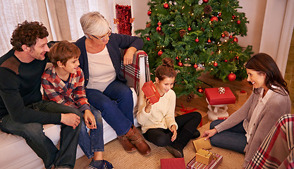 Image showing Christmas, family and open present in lounge, happy and smile together for festive season. Xmas, grandma and parents with children, gifts and happiness for celebration, joy and holiday in living room