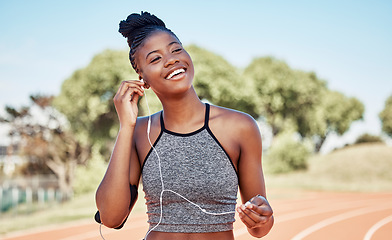 Image showing Earphones, fitness and black woman running on a track for marathon, race or competition training. Sports, workout and athlete runner listening to music, radio or podcast while doing cardio exercise.