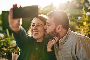 Image showing Love, couple and selfie on a patio by happy people kiss, bond and relax at sunset together. Family, phone and man kissing woman for picture while sitting in a backyard, smile and loving at home