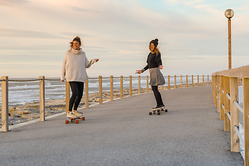 Image showing Two female friends playing with skateboard 