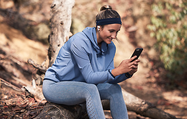 Image showing Fitness, woman with smartphone and earphones for music search, run in the woods with technology and audio streaming for workout. Wellness, happy and runner with radio app and exercise outdoor.