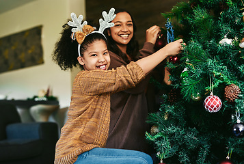Image showing Christmas tree decoration, family and girl with mother helping in home living room. Portrait, festive season and happy child with mom decorating with ornaments and preparing for xmas party in house.