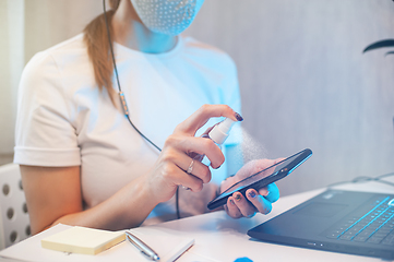 Image showing Woman disinfects the surface of the phone