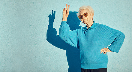 Image showing City, fashion and senior woman with peace sign on blue background wall enjoy freedom, weekend and retirement. Energy, hand sign and happy elderly female with cool, modern and trendy clothes in town