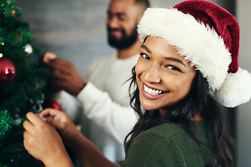 Image showing Couple, portrait and christmas tree decor together with love and care during the festive season. Husband, wife and hanging ornaments on an xmas tree while decorating with tinsel and bauble