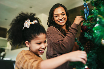 Image showing Christmas tree decoration, family and mother with girl helping in living room. Black family, love and care of happy child bonding with mama, decorating tree and getting ready for xmas party in house.