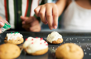 Image showing Girl hands, decorating cookies and closeup with sparkles, cream or candy in kitchen for learning. Family home, child cooking and christmas biscuits on table for domestic skills, education or teaching