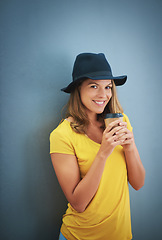 Image showing Woman, fashion or coffee cup on blue background studio and marketing mockup, advertising space or mock up branding. Portrait, smile or happy student and takeaway hot drink, trend hat or style clothes