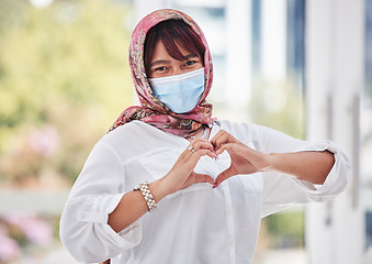 Image showing Muslim, woman with hijab and covid, face mask with hand heart in city portrait, health and love outdoor. Compliance, hands and healthcare with safety and Islam, wellness and covid 19 care and safe.