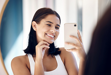 Image showing Mirror selfie, happy woman and phone, beauty and skincare in bathroom of home. Smile young girl taking photograph in reflection, mobile and social media influencer doing morning routine vlog