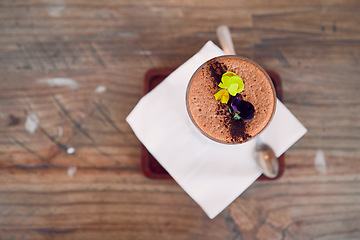 Image showing Coffee shop, barista and hot chocolate art flowers decoration for relaxing and sweet drink break. Cafe, artisan and mocha foam with cocoa powder sprinkle in glass on wood table top view.