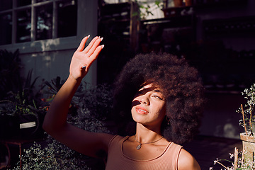 Image showing Sun, shadow and hand with a black woman covering her face from the light while standing outdoor. Beauty, afro and sunlight with an attractive young female blocking her head and skin from sunshine