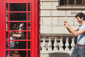 Image showing Couple, phone booth and picture in London, england and travel holiday, summer and fun adventure together in the city. Young man, woman and international vacation, urban town and photo with smartphone