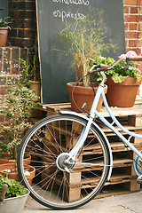 Image showing Bicycle, cafe and small business outdoor restaurant or coffee shop for background in Paris with decoration, plants and menu board. Bike, carbon footprint and street, terrace or patio with wheel