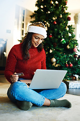 Image showing Christmas, laptop and woman use credit card for payment, happiness or ecommerce for festive season in lounge. Xmas, young female or device for online banking, peace or relax with transaction on floor