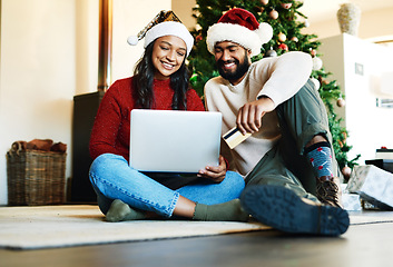 Image showing Laptop, credit card and couple online shopping for christmas gifts together sitting on the floor at home. Ecommerce, deals and young man and woman making sales purchase for xmas presents on computer.