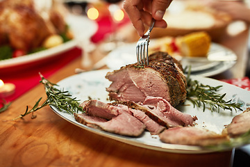 Image showing Hand, fork and beef on a thanksgiving table for tradition or celebration in the holidays closeup from above. Food, meat and Christmas with a place setting on a wooden surface for healthy eating