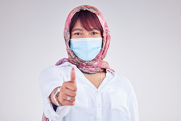 Image showing Covid face mask, muslim woman and thumbs up, portrait and vaccine yes vote, safety compliance and emoji, health risk and policy on studio background. Corona virus, thumb up and islamic female hijab