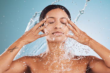 Image showing Water, splash and black woman with shower for beauty and face cleaning, hydration and grooming with blue studio background. Water splash, clean and skincare with hands washing with facial for hygiene