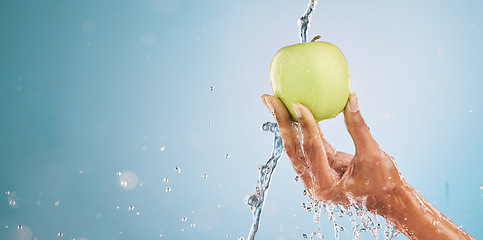 Image showing Water splash, hand of woman and apple in studio on a blue background mockup. Fresh food, cleaning hygiene and female model washing fruit for healthy diet, vitamin c or nutrition, skincare or beauty.