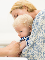 Image showing Child beeing vaccinated by pediatrician in presence of his mother. Preventive vaccination against Diphtheria, whooping cough, tetanus, hepatitis, haemophilus influenzae, pneumococcus, poliomyelitis