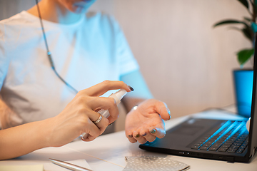 Image showing Woman disinfects the surface of the phone