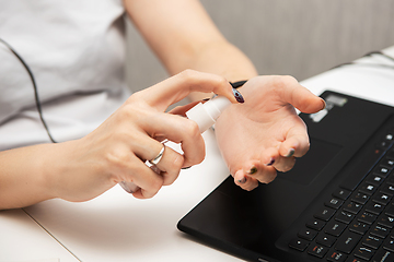 Image showing Woman disinfects the surface of the phone