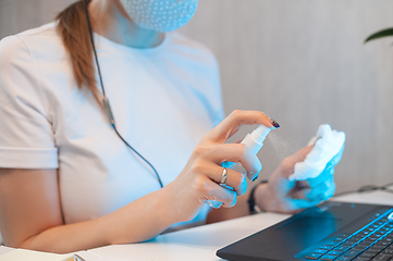 Image showing Woman disinfects the surface of the phone