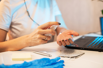 Image showing Woman disinfects the surface of the phone