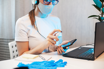 Image showing Woman disinfects the surface of the phone