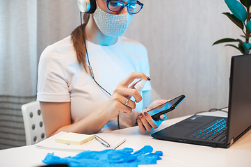 Image showing Woman disinfects the surface of the phone