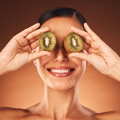 Image showing Face beauty, skincare and woman with kiwi in studio isolated on a brown background. Food, cosmetics and happy female model with fruit for healthy diet, wellness or vitamin c, nutrition or facial care