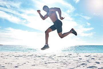 Image showing Fitness, runner and jump of black man at beach for cardio workout, training and wellness body. Summer, run and focus of strong athlete running and jumping on sand at ocean in Los Angeles, USA.