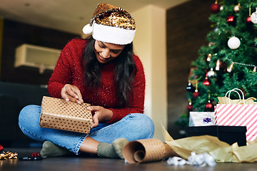 Image showing Woman, Christmas and gift wrapping by the tree for festive season, holiday or special surprise at home. Happy excited female busy with gifting wrap, box or present for December celebration indoors