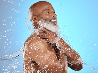 Image showing Beauty, water and cleaning splash of senior man for body care, hygiene and health lifestyle. Happy, shower and mature black model washing skin at studio blue background with satisfied smile.