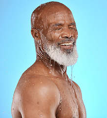 Image showing Water splash, skincare and face of senior black man in studio isolated on a blue background. Cleaning, hygiene and retired elderly male from Nigeria bathing or washing for wellness and healthy skin.