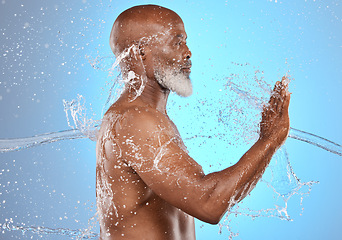 Image showing Black man, skincare and water splash for beauty, cosmetics and dermatology on blue studio background for old age skin and body. Model cleaning, washing and shower for hygiene, health and wellness