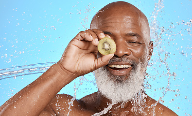 Image showing Skincare, kiwi and senior man in studio for beauty, water splash and wellness on blue background mockup. Beauty splash, fruit and water with elderly man cleaning, happy and relax with nature product