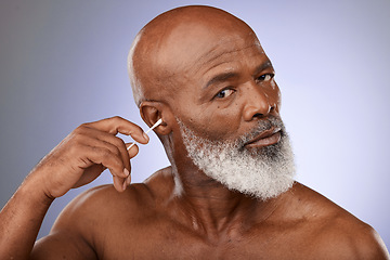 Image showing Black man, cleaning ear and cotton bud for hygiene, wellness and wax with face, portrait and purple studio background. Senior male with ears, cleaner and self care for earwax , remove and stick