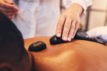 Image showing Hands, hot stone and massage with a man in a spa, lying on a table or bed for stress relief and wellness. Relax, luxury and rock with a male customer in a health salon for physical therapy