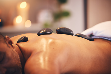 Image showing Massage, hot stone and relax with a man in a spa, lying on a table or bed for physical therapy at a luxury resort. Wellness, rock and zen with a male customer relaxing in a health center for rest