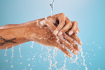 Image showing Black woman, water splash or washing hands on blue background in studio for hygiene maintenance, healthcare or wellness. Zoom, wet model or cleaning fingers for bacteria security or virus risk safety