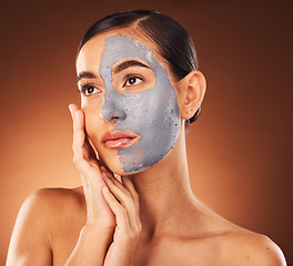 Image showing Woman, face skincare and mud mask on orange background in studio self care, dermatology or acne treatment. Beauty model, facial mud and cream product for collagen maintenance, cleaning detox or scrub