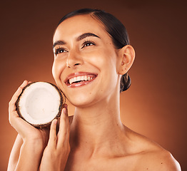 Image showing Coconut, skincare and beauty woman marketing food, thinking wellness and spa facial against a brown studio background. Health, cosmetics and model with a natural oil product for skin glow and detox