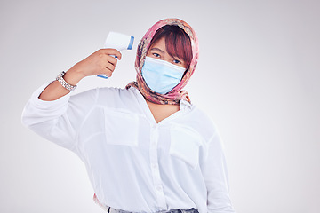 Image showing Muslim woman, covid face mask and thermometer gun on white studio background for marketing, virus and healthcare mockup. Portrait of islam model in hijab with medical thermal scanner for safety